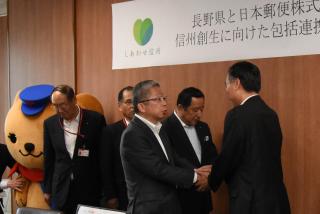 写真：日本郵便との包括連携協定締結式で、握手を交わす知事と日本郵便の方