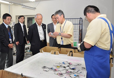 写真：インクカートリッジの仕分け作業を視察する村井知事