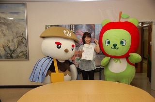 写真：表彰状を手に信州なび助とアルクマに囲まれる小林さん