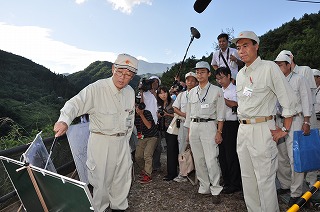 写真：工事現場を災地を視察職員から進ちょく状況を聞く阿部知事