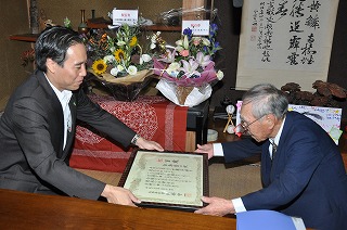 写真：白鳥さんにお祝い状を渡す知事