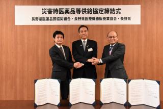 協定書を前に握手を交わす医薬品や医療機器販売の業界代表者らと知事の写真
