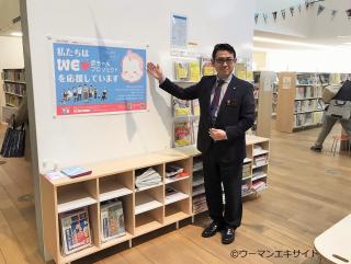 写真：「WEラブ赤ちゃんプロジェクト」賛同ポスターを掲示する塩尻市立図書館の上條館長