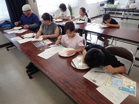 写真１　食味官能審査を体験するご家族 　「おいしいお米はどれだろう？」 真剣です！